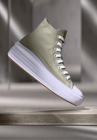 Sneaker alta in tela verde oliva con suola in gomma bianca, punta tonda e occhielli bianchi. Design minimalista con texture liscia.