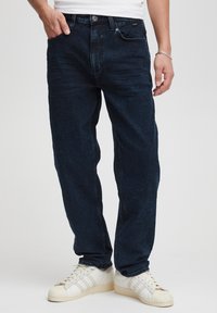 Jeans in denim blu scuro con vestibilità ampia, dotati di tasche frontali, chiusura con bottone e leggere sfumature sul tessuto.