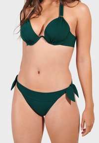 Ciemnozielony bikini z usztywnianym, drucianym stanikiem z marszczeniami i cienkimi ramiączkami, w komplecie z dopasowanym dołem hipsterskim z akcentami w postaci kokardek.