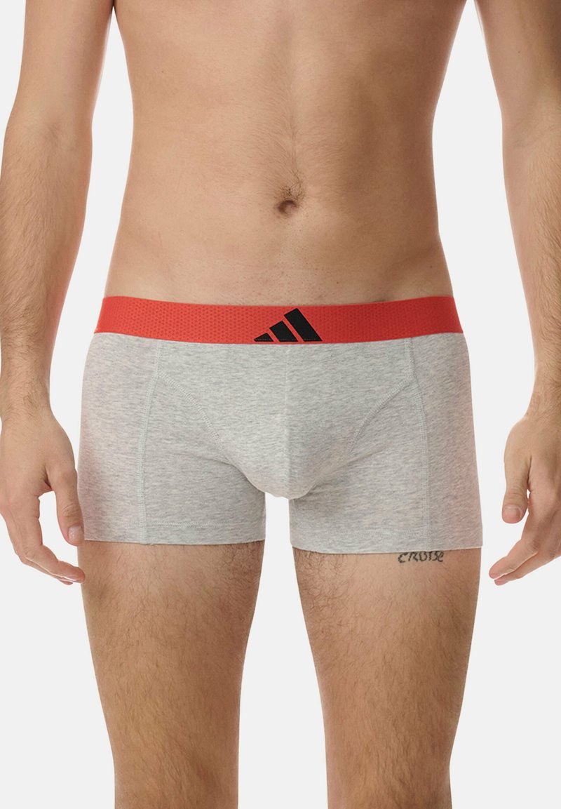 Boxer in cotone grigio con elastico rosso in vita e logo Adidas nero. Tessuto liscio e design aderente.