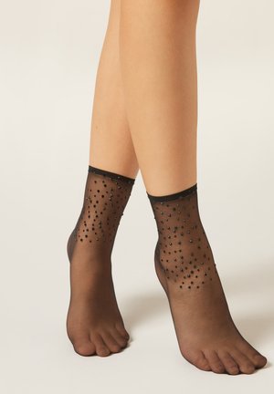 Schwarze transparente Knöchelsocken mit einem Muster aus kleinen schwarzen Perlen, glattem Stoff und einem elastischen Bündchen oben.
