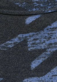 Stickad tyg i mörkgrått med ett blått abstrakt mönster. Slät textur med varierande nyanser av blått som skapar djup och visuell intresse.