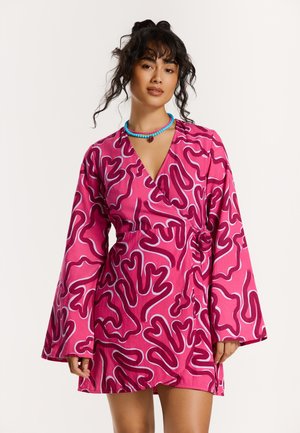 Pink wrap dress featuring abstract white and dark pink patterns, long bell sleeves, and a tie at the waist. Smooth texture, casual design.
