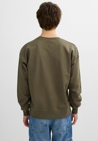 Sudadera verde olivo con cuello redondo, hombros caídos, puños acanalados y dobladillo. El material parece suave y ligeramente texturizado.