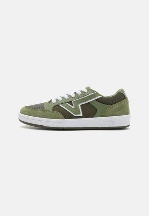 Baskets basses Vans vert olive avec lacets blancs, bande logo blanche, panneaux en daim et mesh, et semelle en caoutchouc blanche.