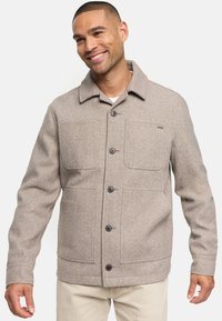 Veste en tissu gris avec fermeture à boutons, deux grandes poches poitrine et un col de chemise. Présente une finition texturée et une coupe ajustée.