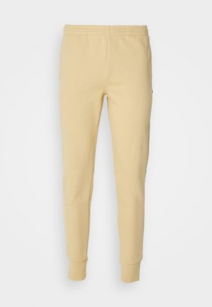 Pantalones de chándal amarillos de algodón con cintura elástica, piernas ajustadas y puños acanalados. Presenta un pequeño logo en la parte superior.