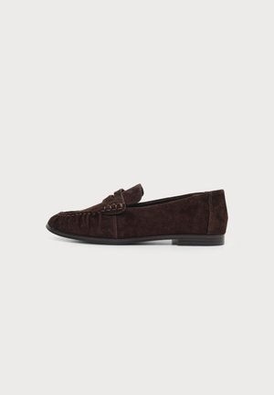 Mocassin en daim marron foncé avec un petit talon, couture style mocassin et une bride décorative sur le dessus.