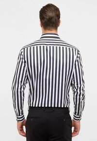 Zwart-witte gestreepte shirt met lange mouwen, knoopsluiting bij de kraag en manchetten, gecombineerd met zwarte broek.