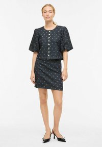 Ensemble deux pièces en denim foncé comprenant un haut court à larges manches bouffantes et fermeture par boutons, associé à une jupe ajustée, tous deux ornés de pois.