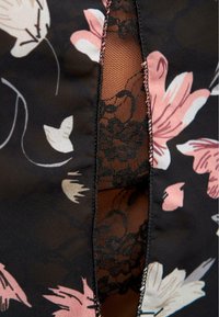 Abito floreale realizzato in un tessuto trasparente nero con motivi floreali rosa e bianchi. Il design include un pannello in pizzo e dettagli cuciti.