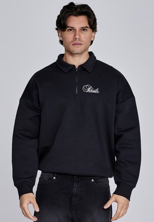 Sudadera negra con cuello con cremallera, ajuste holgado y logo en el lado izquierdo del pecho. Fabricada con material suave, con mangas texturizadas y de color sólido.