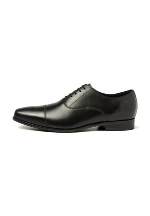 Chaussure habillée en cuir noir avec un bout pointu, dotée d'un système de laçage fermé et de détails de couture minimalistes. Talon plat avec un marquage discret.
