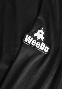 Sort stof har en tekstureret overflade med et fremtrædende sort og hvidt gummimærke, der siger "WeeDo" med et raketdesign.