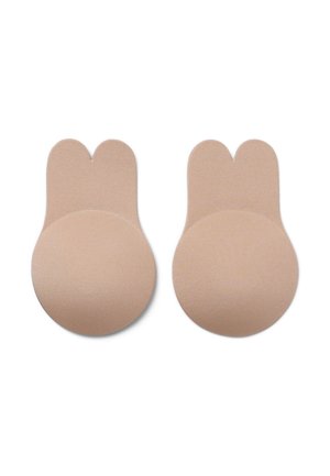 Nude samoprzylepne pastylki w kształcie zaokrąglonych uszu królika, charakteryzujące się gładką fakturą i bezszwowym designem, umożliwiającym dyskretne noszenie pod odzieżą.