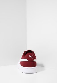 Chaussures de sport bordeaux avec une tige en tissu lisse, des accents blancs, un col rembourré et une semelle épaisse en caoutchouc blanc. Présente un logo sur le talon.
