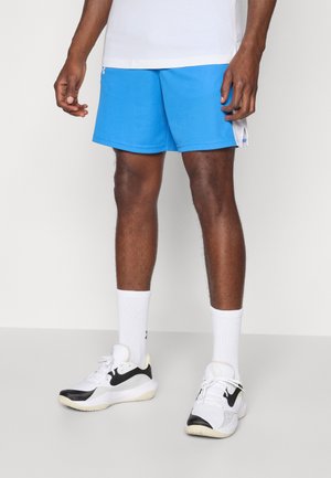 Blaue Sportshorts aus leichtem Material mit glatter Textur. Weiße Akzente an den Seiten, kombiniert mit weißen und schwarzen Sneakers.