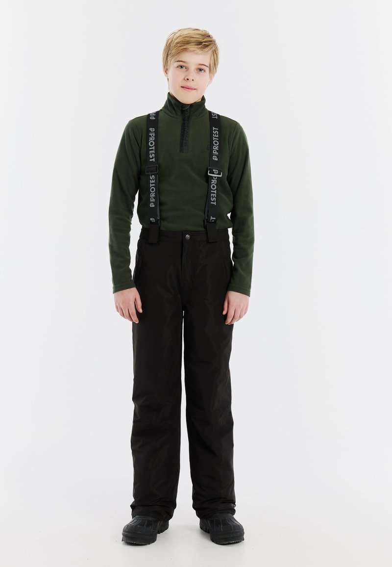 Groene fleece top met lange mouwen en een ritssluiting bij de kraag, gecombineerd met zwarte geïsoleerde broeken en zwarte laarzen. De broeken hebben verstelbare bretels.