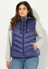 Granatowa kamizelka puchowa z wzorem w zygzaki, zipem z przodu oraz regulowanym kapturem ze sznurkiem. Lekki materiał z bocznymi kieszeniami.