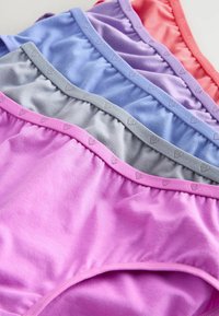 Cinq paires de sous-vêtements en coton rose, gris, bleu, violet et corail, chacune avec une ceinture embossée d’un cœur, soigneusement superposées sur une surface blanche.
