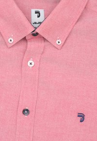 Roze overhemd met kraag, gemaakt van textiel met een structuur. Bevat witte knopen met donkere knoopsgaten en een klein blauw logo op de borst.