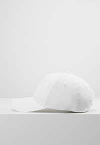 Cappello bianco con visiera arcuata, realizzato in tessuto liscio. Presenta cuciture minime e un piccolo dettaglio del logo sul pannello frontale.