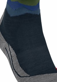 Ingrandimento di una calza alla caviglia con blocchi di colore blu navy, grigio, verde e blu e motivi a maglia testurizzata per supporto e comfort.