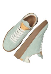 Zapatillas de ante verde menta con cordones blancos, suela de goma y detalles en cuero marrón en la lengüeta y el talón. Presentan costuras decorativas.