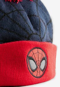 Bonnet tricoté avec un dessus bleu marine présentant un motif en toile d'araignée et un revers rouge. Visage de Spider-Man brodé en noir, blanc et rouge sur le revers.