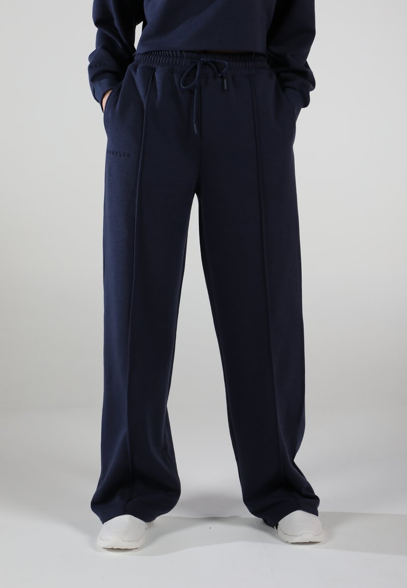 Navy blue sweatpants with a relaxed fit, featuring an elastic waistband, drawstring, side pockets, and subtle stitched detailing.