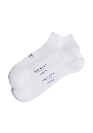 Calzini bianchi alla caviglia realizzati in materiale morbido, con un piccolo logo e testo di branding in blu scuro, che evidenziano l'artigianalità e la qualità.