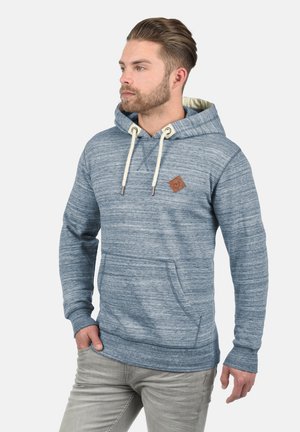 Plava heathered dukserica s kengurujem, vezicama i malim smešnim kožnim logom. Mekana tekstura tkanine i ležeran kroj.