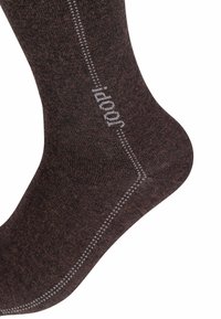 Calzino marrone realizzato in materiale testurizzato con logo e dettagli di cucitura grigio chiaro. Caratterizzato da una vestibilità aderente con tallone rinforzato.