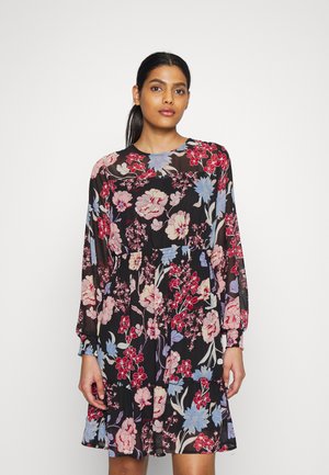 Vestido preto com padrão floral, incluindo mangas longas, gola redonda e bainha em camadas. O padrão apresenta flores vermelhas e azuis em um tecido transparente.