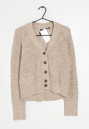 Cardigan beige en tricot avec cinq boutons marron, manches longues, poignets et ourlet côtelés, présenté sur un cintre noir contre un fond blanc.