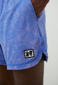 Blaue Sportshorts mit einem Batik-Look, mit einem schwarzen Nike-Logopatch am Saum. Hergestellt aus leichtem Material mit einer lockeren Passform.