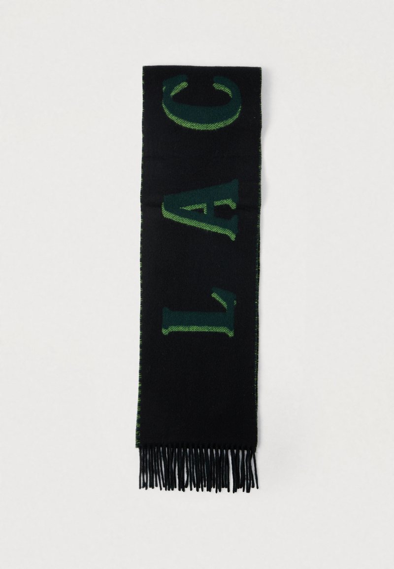 Cachecol preto com letras verdes em destaque e bordas com franjas. Feito de material macio, apresenta um design simples mas marcante.