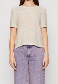 Gebreide top met korte mouwen in lichtbeige, met een klassieke ronde halslijn en een ontspannen pasvorm. Textuur met een iets losse weving.