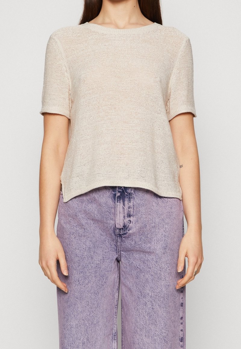 Gebreide top met korte mouwen in lichtbeige, met een klassieke ronde halslijn en een ontspannen pasvorm. Textuur met een iets losse weving.