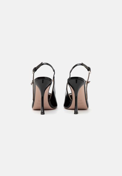 Zapatos de charol negro de tacón alto con diseño de slingback, punta afilada y tacón delgado tipo stiletto. Textura suave, hardware minimalista.