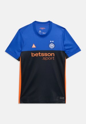 Maillot de sport bleu et noir avec texte orange "betsson.sport", bandes latérales orange, et un logo circulaire avec deux étoiles sur la poitrine.
