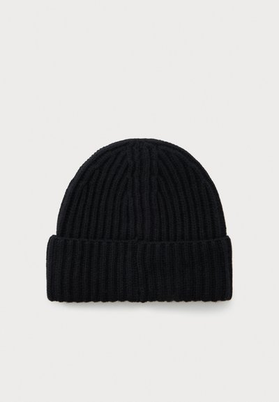 Must kaugemust kammitud beanie müts, millel on volditud äär ja soonikkoes vertikaalne muster, lamab tasasel valgel taustal.