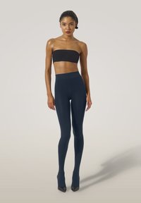 Navyblå leggings lavet af strækbart stof med høj talje, parret med en sort stropløs top og sorte spidse hæle.