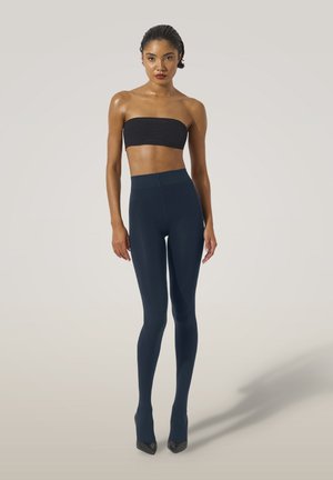 Mörkblå leggings i stretchmaterial med hög midja, kombinerade med en svart strapless-topp och svarta spetsiga klackar.