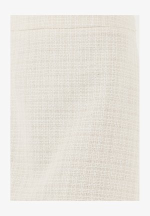 Gros plan d'un tissu tissé couleur crème avec un motif de grille subtil et des fils texturés.