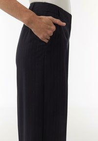 Dunkel gestreifte Hosen mit maßgeschneiderter Passform, ausgestattet mit einer Seitentasche und einer glatten Textur. Der Stoff ist leicht und eignet sich für formelle Anlässe.