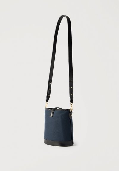 Σκουρο μπλε τσάντα κουβάς με μαύρη βάση από δέρμα και ρυθμιζόμενο λουράκι ώμου, χρυσά μεταλλικά στοιχεία και μικρή χρυσή ετικέτα με το λογότυπο "W".