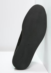 Suola di una scarpa nera con texture liscia e numero di taglia 41 impresso al centro su uno sfondo bianco.