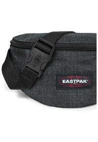 Černý denimový ledvinkový batoh s zipovým uzávěrem, nastavitelným popruhem a logem Eastpak. Kompaktní, měkká textura s jemným vzorem.