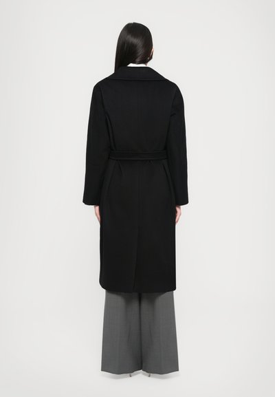 Black wool coat with a belted waist, long sleeves, and a notched collar, shown from the back. Paired with gray wide-leg trousers.